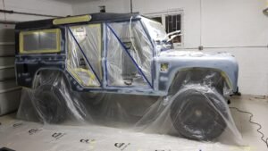 A technician applying Raptor protective paint to the body panels in the paint booth.