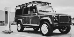 A custom Land Rover Defender with an electric motor conversion, plugged into a charging station.